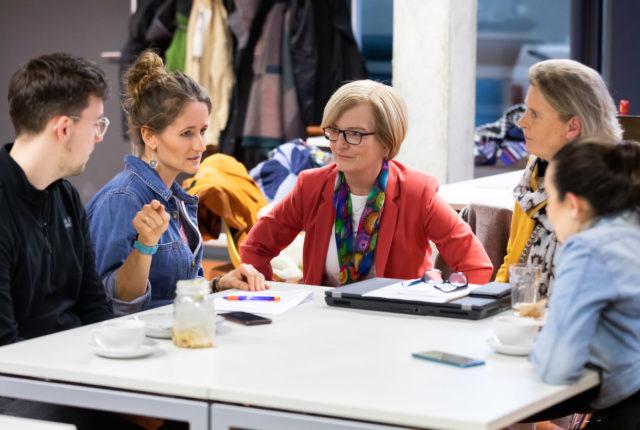 Foto von Ulrike Tippe im Gespräch mit Hochschulmitarbeiter:innen